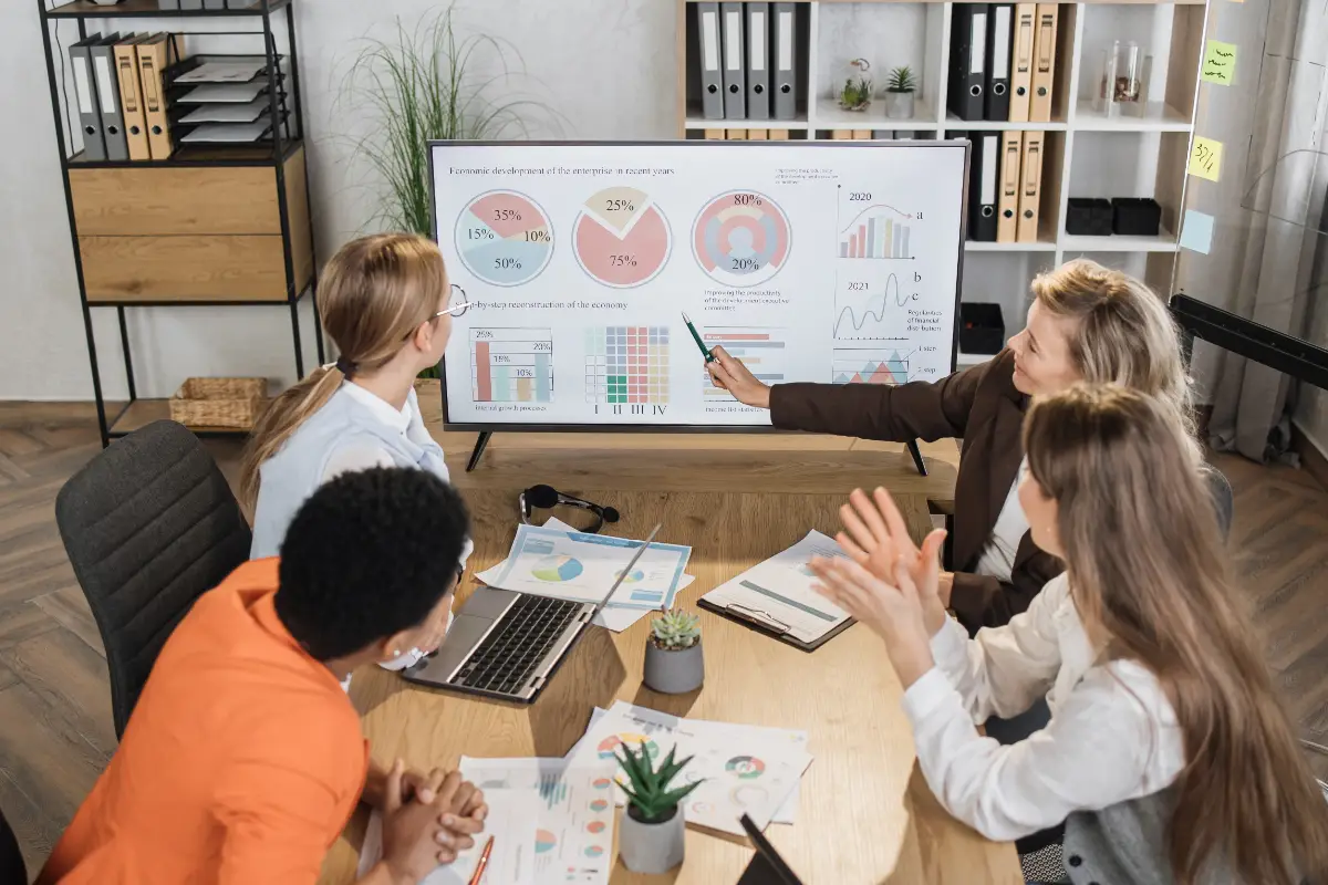 Group of business people around table looking over stats in presentation