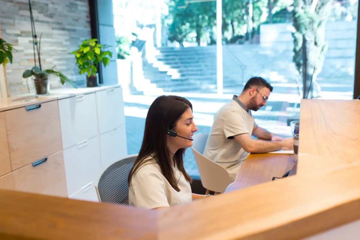 Two receptionists working at the front desk of medium sized business